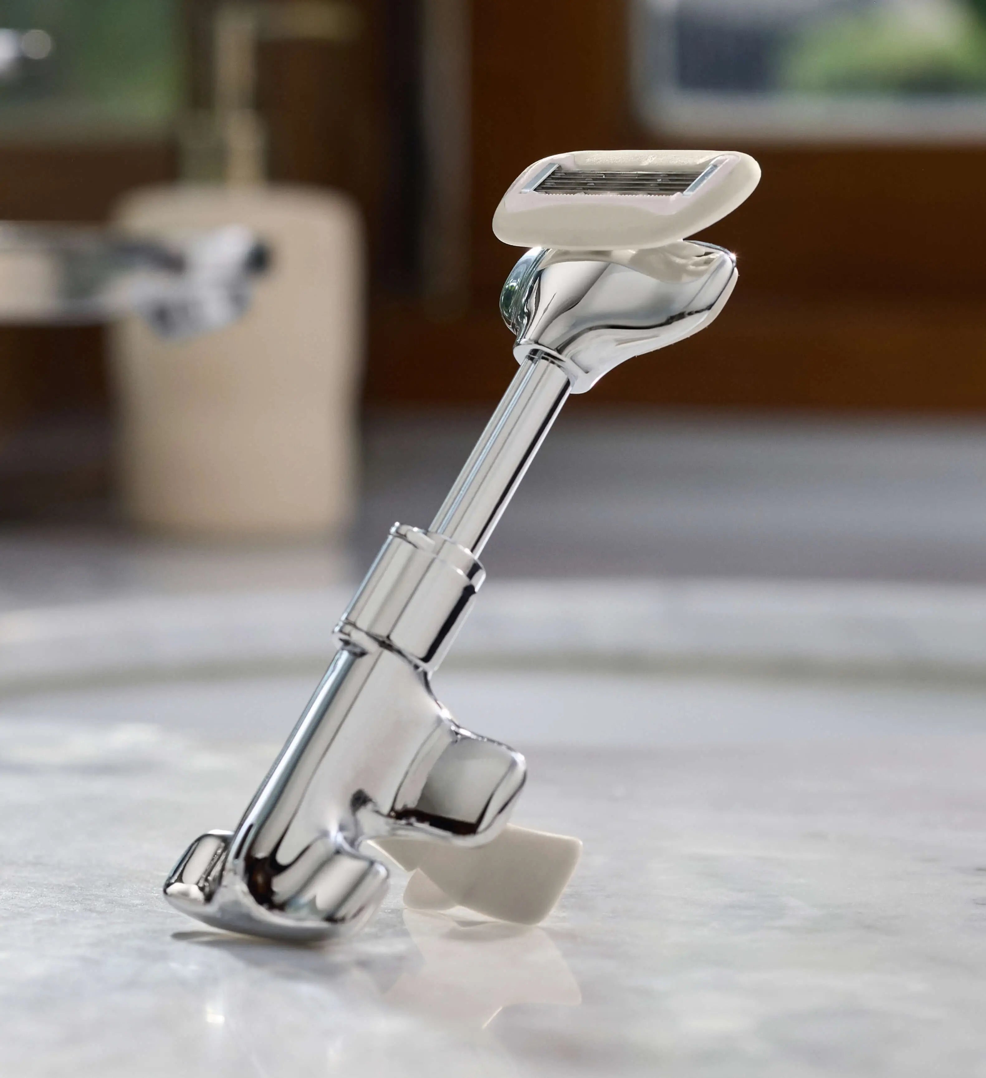 Metal shaving razor on a marble countertop with blurred background