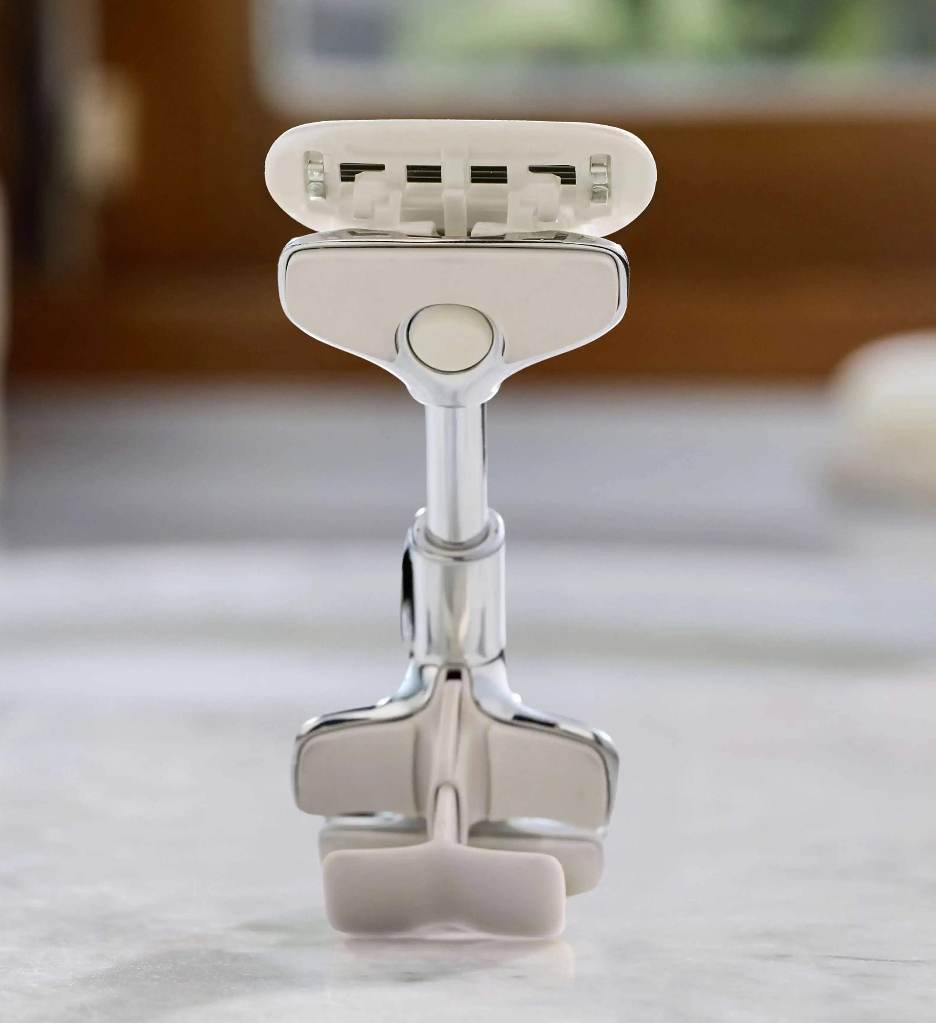 Silver razor on a white surface with a blurred background