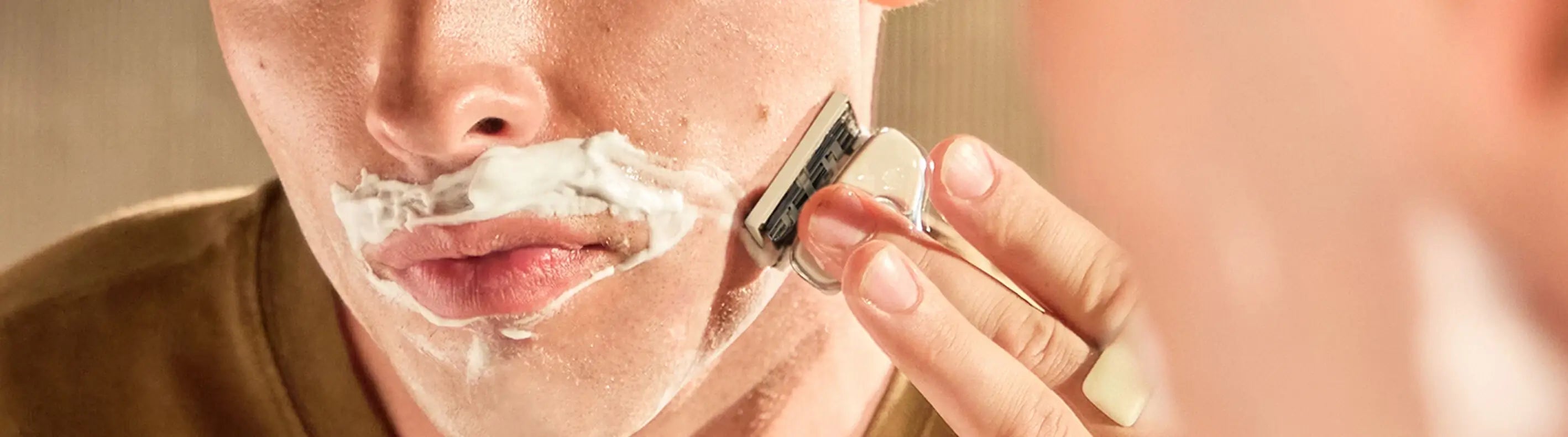 Person shaving with a razor, close-up of face