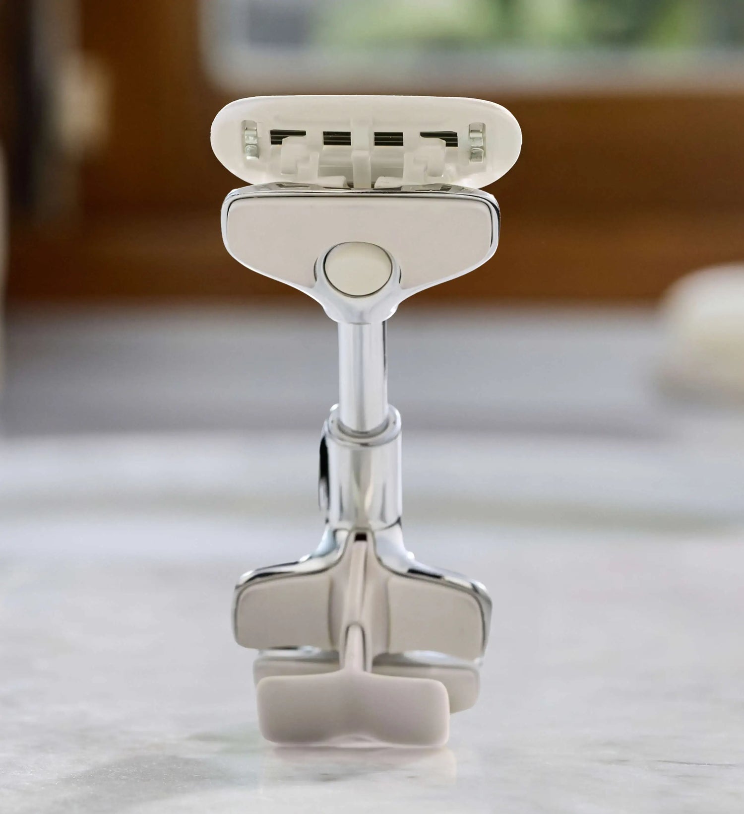 Silver razor on a white surface with a blurred background