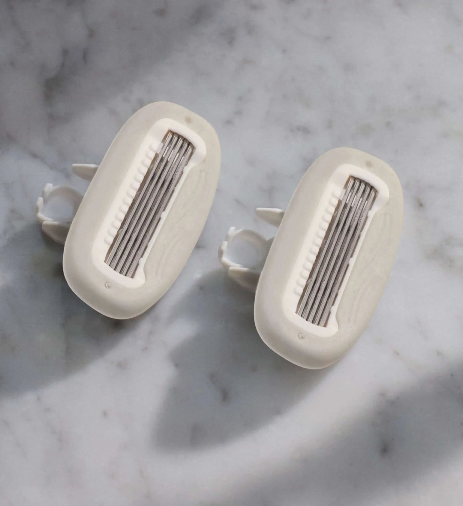 Two razor blade cartridges on a marble countertop