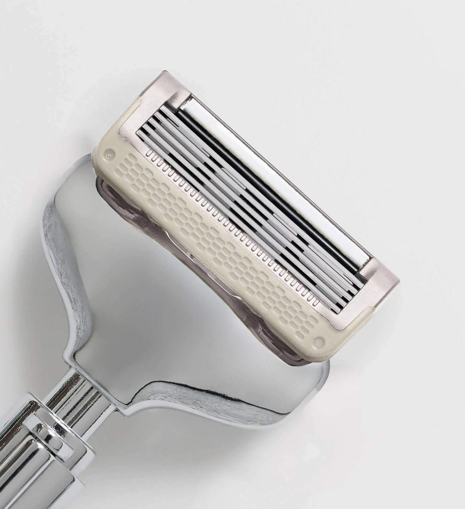 Close-up of a metallic razor on a light gray background