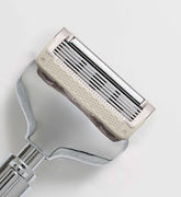 Close-up of a metallic razor on a light gray background