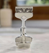 Silver safety razor on a marble surface with a blurred background