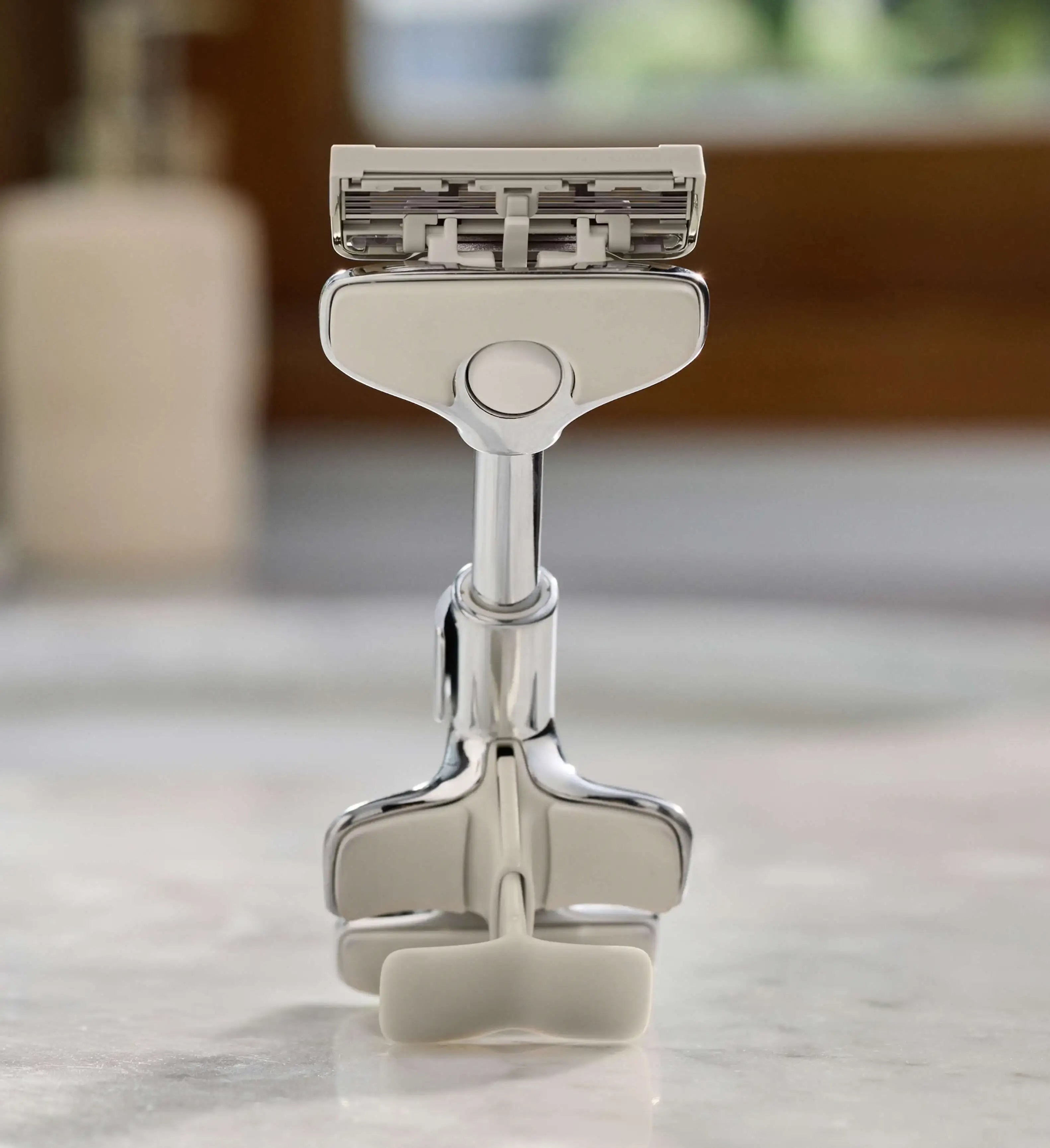 Silver safety razor on a marble surface with a blurred background
