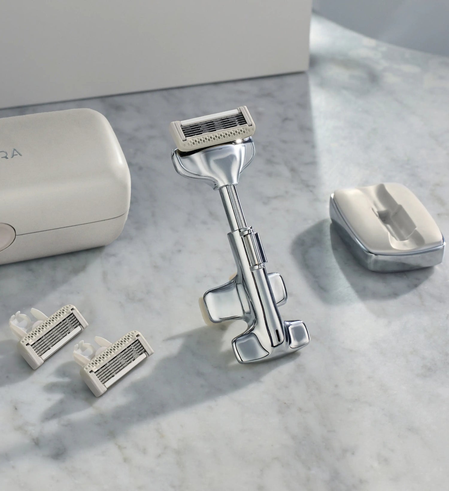 Shaving system with razor, shaver head, and packaging on a marble surface