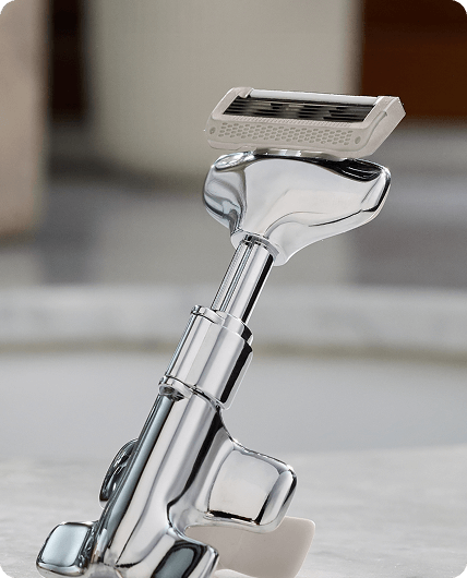 Shiny metal razor on a light wooden surface