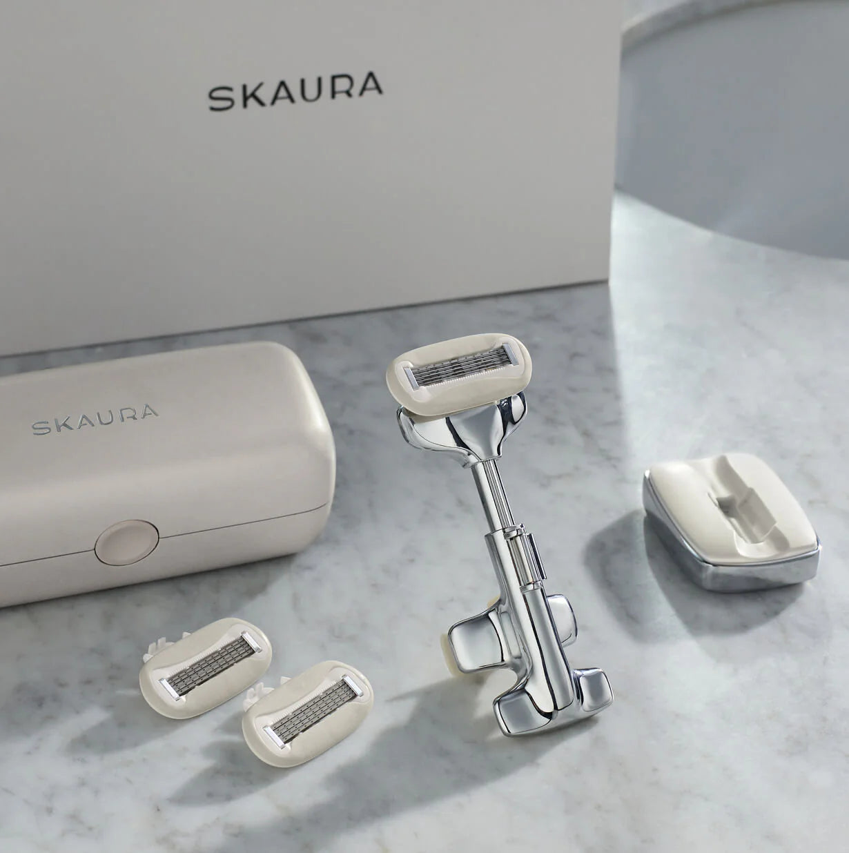 Skaura razor and accessories on a marble surface with 'Skaura' branding.